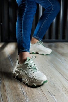 Sports shoes for women. Slender female legs in jeans and white stylish casual sneakers. Comfortable women's summer shoes. Casual women's fashion.