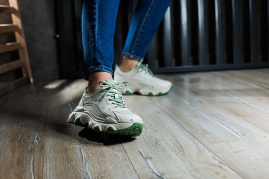 Sports shoes for women. Slender female legs in jeans and white stylish casual sneakers. Comfortable women's summer shoes. Casual women's fashion.