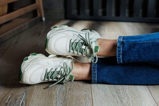 Sports shoes for women. Slender female legs in jeans and white stylish casual sneakers. Comfortable women's summer shoes. Casual women's fashion.