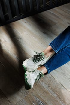 Sports shoes for women. Slender female legs in jeans and white stylish casual sneakers. Comfortable women's summer shoes. Casual women's fashion.