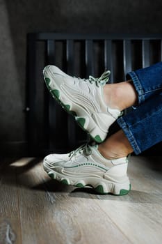 Sports shoes for women. Slender female legs in jeans and white stylish casual sneakers. Comfortable women's summer shoes. Casual women's fashion.