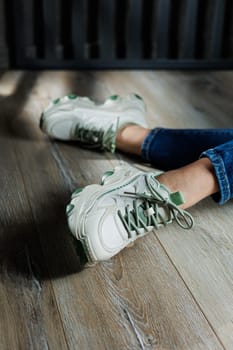 Sports shoes for women. Slender female legs in jeans and white stylish casual sneakers. Comfortable women's summer shoes. Casual women's fashion.