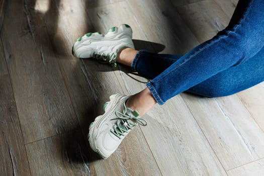 Sports shoes for women. Slender female legs in jeans and white stylish casual sneakers. Comfortable women's summer shoes. Casual women's fashion.