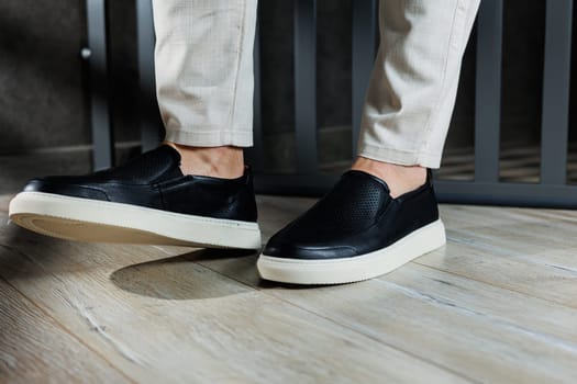 Male legs in leather shoes. Comfortable men's black shoes without laces. Casual men's moccasins