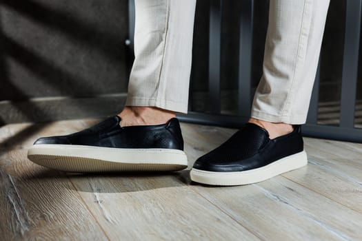 Male legs in leather shoes. Comfortable men's black shoes without laces. Casual men's moccasins