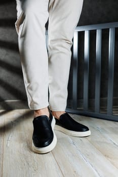 Male legs in leather shoes. Comfortable men's black shoes without laces. Casual men's moccasins