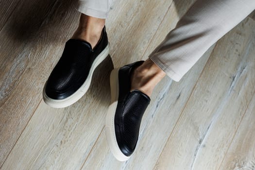 Male legs in leather shoes. Comfortable men's black shoes without laces. Casual men's moccasins