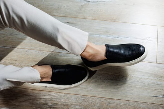 Male legs in leather shoes. Comfortable men's black shoes without laces. Casual men's moccasins