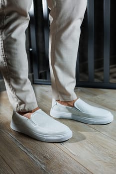 Male legs in leather summer shoes. Comfortable men's white moccasins without laces. Casual men's moccasins