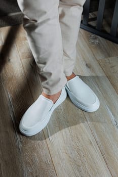 Male legs in leather summer shoes. Comfortable men's white moccasins without laces. Casual men's moccasins