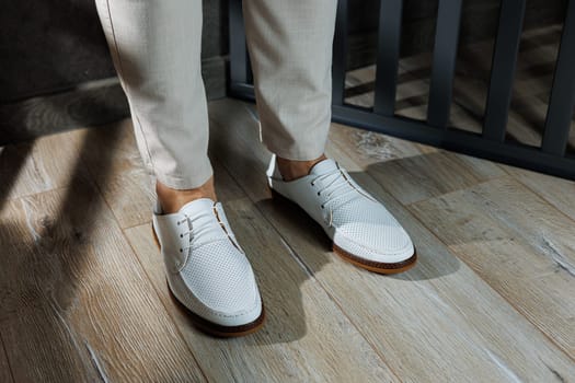 Male legs in leather summer shoes. Comfortable men's white moccasins without laces. Casual men's moccasins