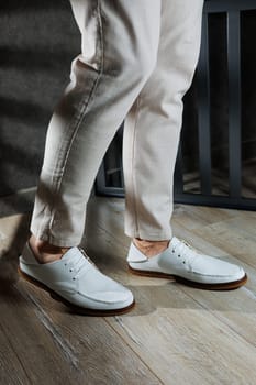 Male legs in leather summer shoes. Comfortable men's white moccasins without laces. Casual men's moccasins