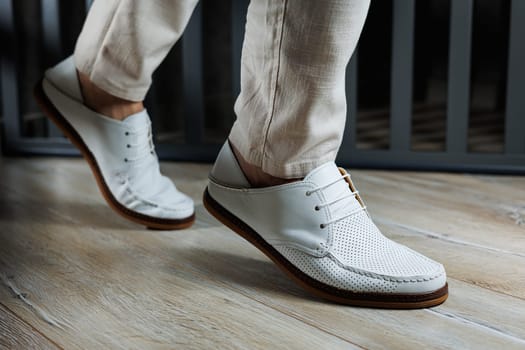 Male legs in leather summer shoes. Comfortable men's white moccasins without laces. Casual men's moccasins