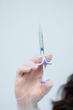 Female hand in gloves with syringe in hand. Syringe for injections in cosmetology