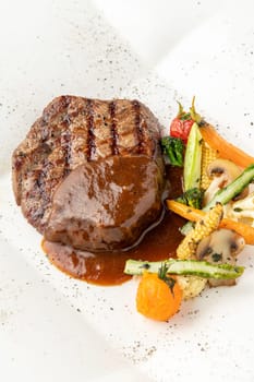 Grilled beef tenderloin with Demi glace sauce with grilled vegetables on a white porcelain plate