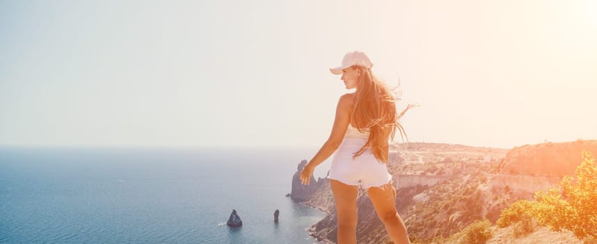 Woman travel sea. Young Happy woman in a long red dress posing on a beach near the sea on background of volcanic rocks, like in Iceland, sharing travel adventure journey