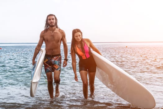 Sea woman and man on sup. Silhouette of happy young woman and man, surfing on SUP board, confident paddling through water surface. Idyllic sunset. Active lifestyle at sea or river