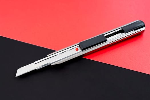 A cutter knife or stationery knife on black and red color background.