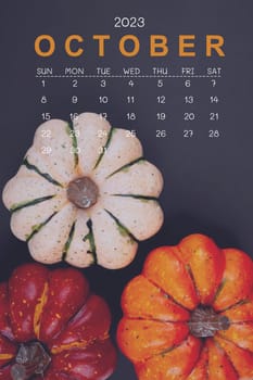 October 2023 Calendar and pumpkins on black cardboard background.