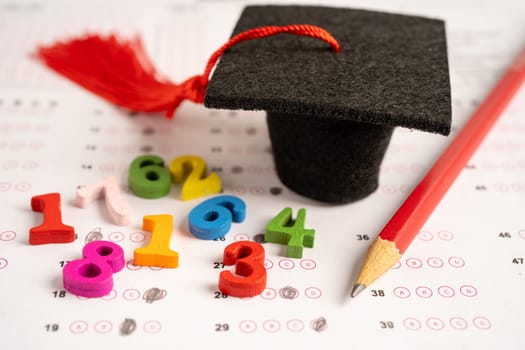 Graduation gap hat and pencil on answer sheet paper, Education study testing learning teach concept.