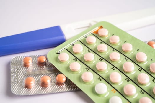 Pregnancy test and birth control pills on calendar, contraception health and medicine.