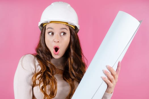 Portrait young woman architect with long hair looking excited holding her project in her hands on the pink background