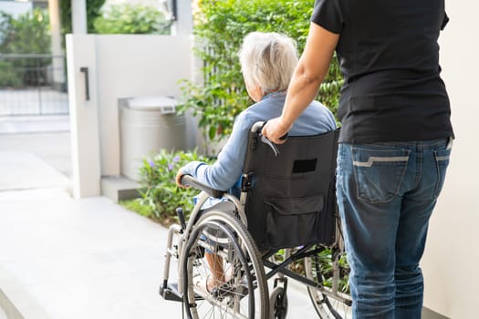 Caregiver help and care Asian elderly woman patient sitting on wheelchair to ramp in nursing hospital, healthy strong medical concept.