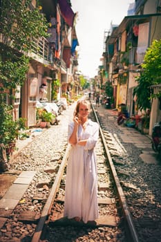 Travel keeps the soul fulfilled. a young woman walking on train tracks through the streets of Vietnam