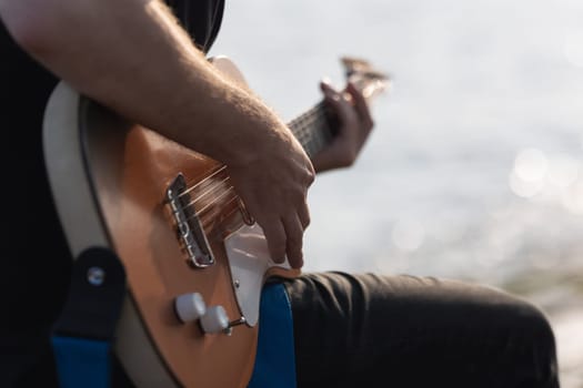 Playing electric guitar by the river. Mid shot