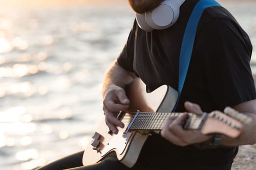 Playing guitar at the waterfront. Mid shot