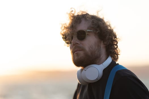 A man wearing wireless headphones at sunset. Portrait