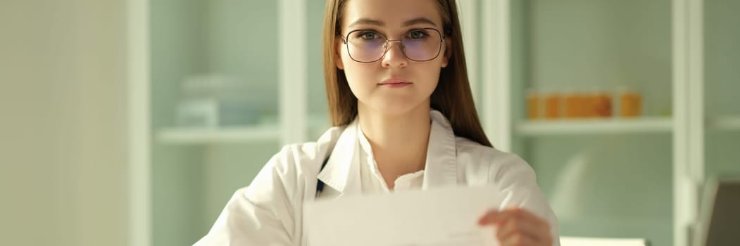 Doctor cardiologist examining patient cardiogram on paper in clinic. Diagnosis of heart disease concept