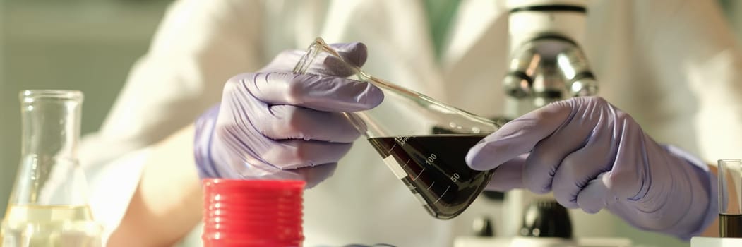 Scientist chemist holding in his hands flask with oil in chemical laboratory closeup. Quality control of composition of petroleum products concept