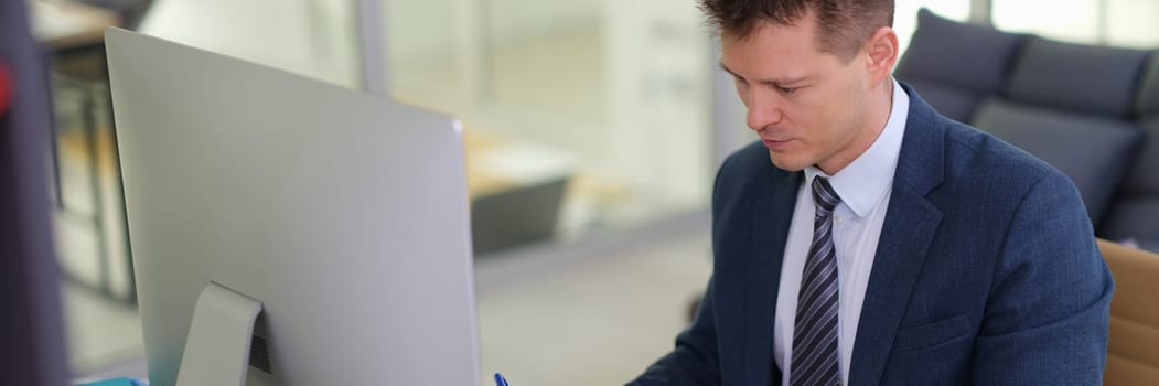 Businessman studying paper document in front of computer in office. Business strategy concept