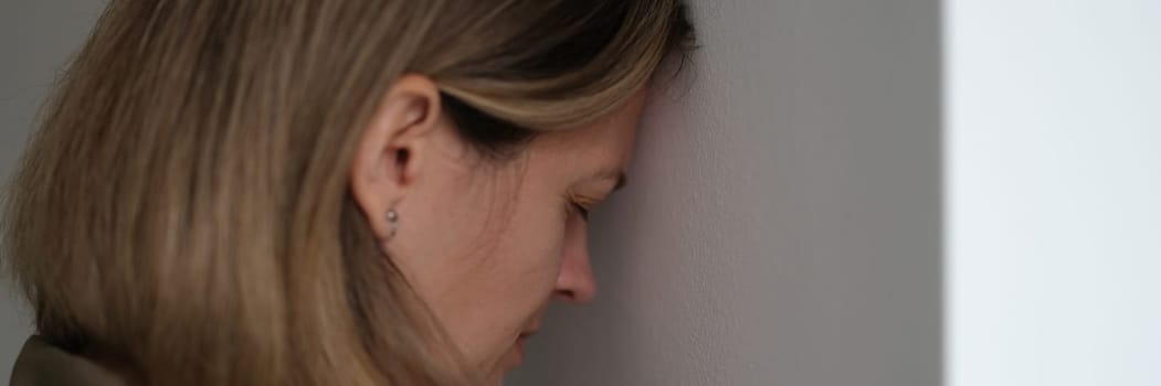 Tired depressed woman banging her head against wall. Hopeless situations concept