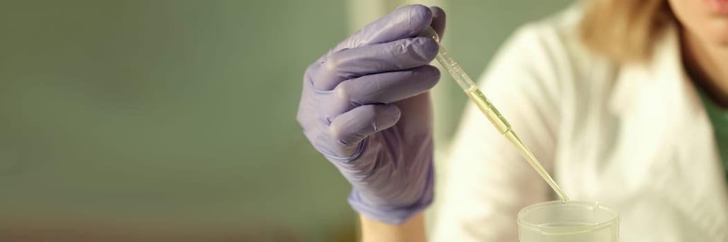 Doctor of chemical sciences in gloves dripping yellow liquid from test tube in laboratory closeup. Urine analysis concept