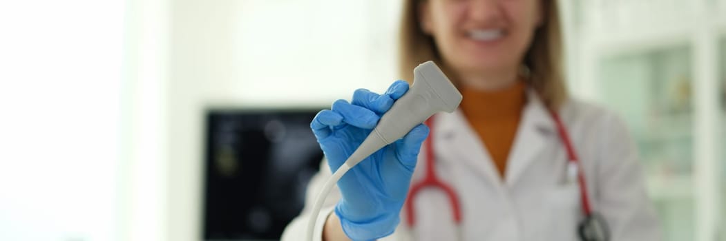 Smiling woman ultrasound diagnostic doctor holding transducer in clinic closeup. Instrumental diagnostics of gynecology examination of pregnant women concept