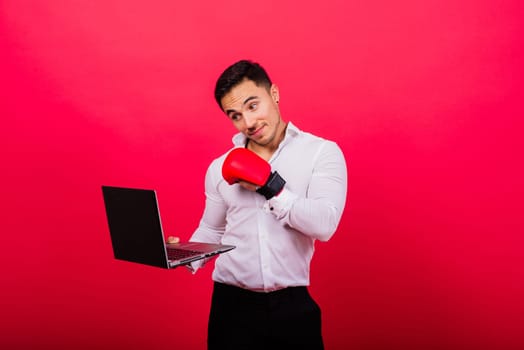 Guy in boxing gloves and formalwear punch computer isolated on a red, cyber bullying.