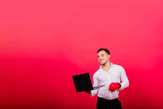 Guy in boxing gloves and formalwear punch computer isolated on a red, cyber bullying.