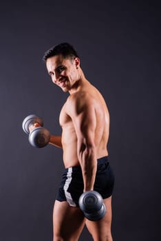 Shirtless bodybuilder showing his great body and holding dumbells.