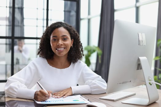 woman sitting at desktop with laptop noting down important information