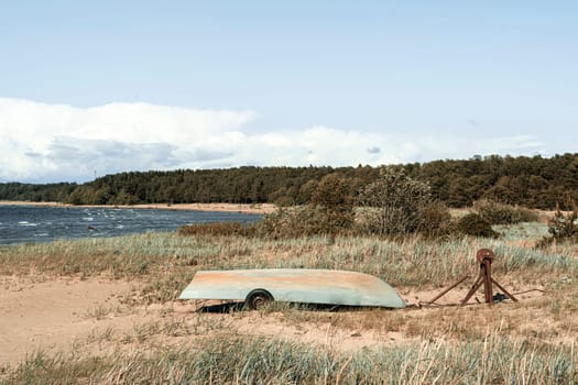 Old fishing boats pulled out on the sandy shore of the sea bay in sunny weather. Fishermen's boats are resting on the shore lying upside down