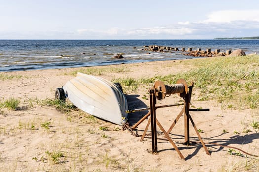 Old fishing boats pulled out on the sandy shore of the sea bay in sunny weather. Fishermen's boats are resting on the shore lying upside down