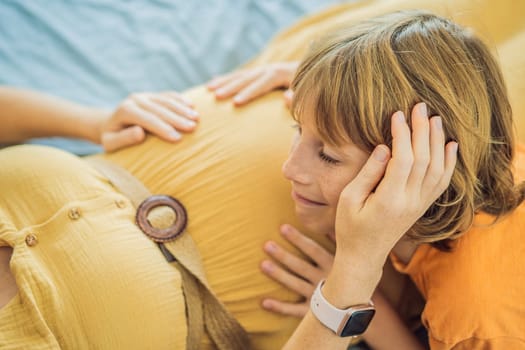 Young pregnant mother hugging her little boy lying in bed at night. Caring and loving parent hugging child.