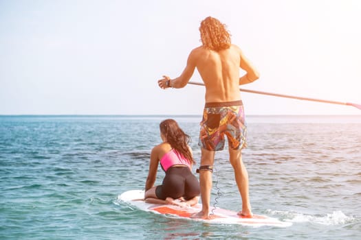 Silhouette of woman standing, surfing on SUP board, confident paddling through water surface. Idyllic sunset or sunrise. Sports active lifestyle at sea or river.