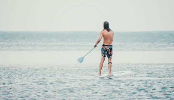 Sea woman and man on sup. Silhouette of happy young woman and man, surfing on SUP board, confident paddling through water surface. Idyllic sunset. Active lifestyle at sea or river