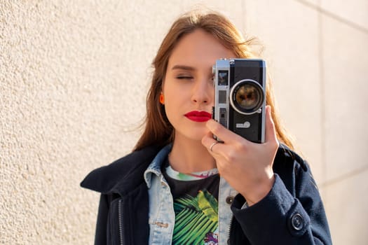 Portrait of a pretty young tourist taking photographs with vintage retro camera. Street style. Life style