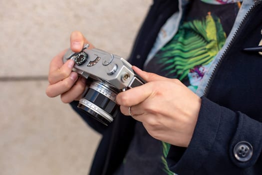 Girl photographer with an old camera in his hands. Stylish fashionable girl photographer in the city street