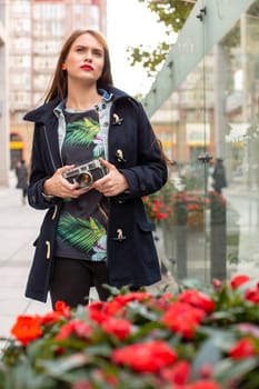 Outdoor autumn smiling lifestyle portrait of pretty young woman, having fun in the city with camera, travel photo of photographer. Making pictures in hipster style.