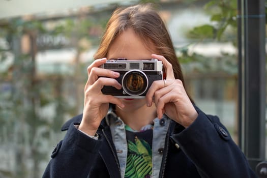 Portrait of a pretty young tourist taking photographs with vintage retro camera. Street style. Life style